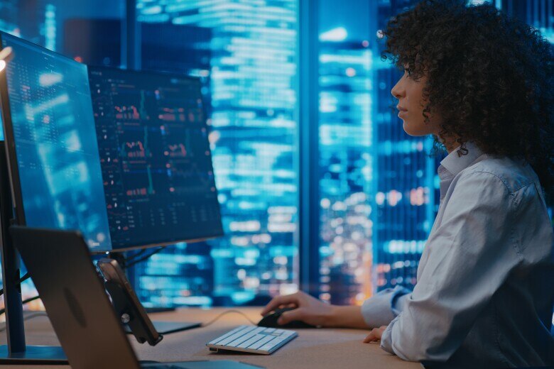 programmer/manager sits in front of computer in the office, analyzing graphs