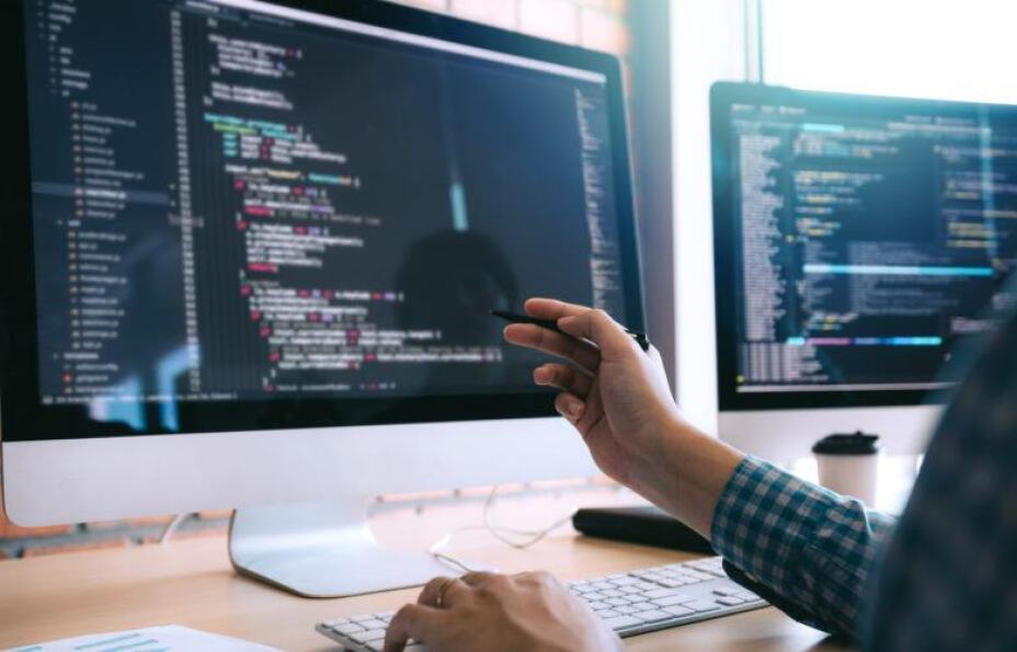 A DevOps professional reviews code on a computer monitor