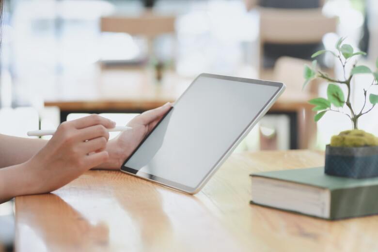 person leaning on wooden table holding white tablet