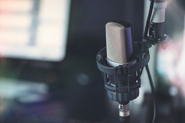 Close up of microphone in radio broadcast studio and computer screens on the background