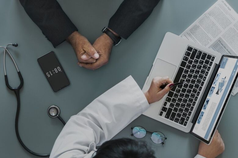 aerial view of doctor showing her patient information on her laptop