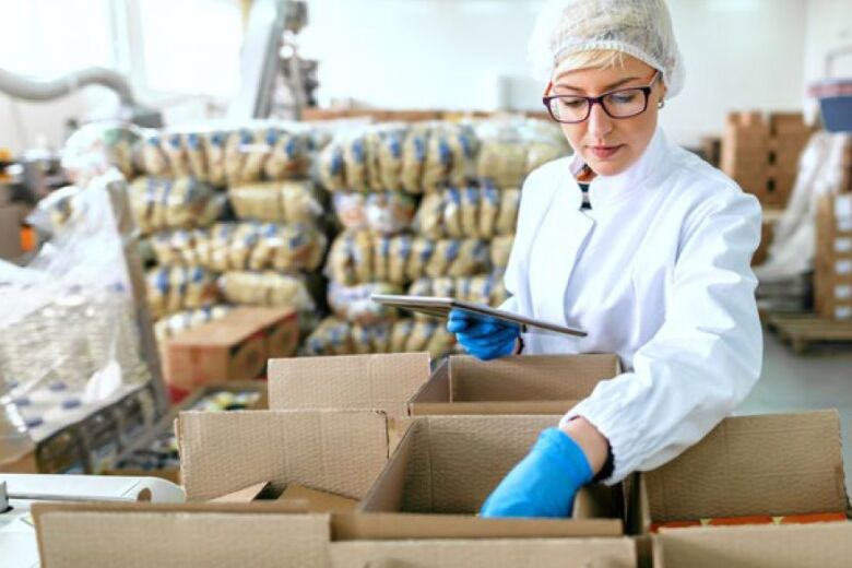 woman wearing protective gear while checking an order in a food processing warehouse