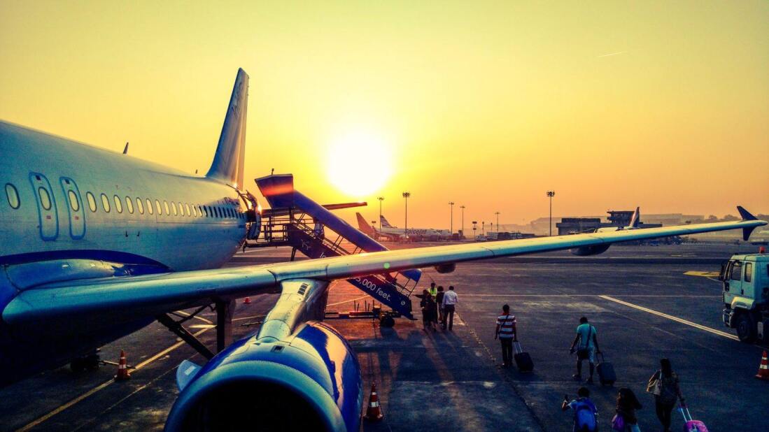 passengers walking along the tarmac and climbing stairs to board a large jet at dusk