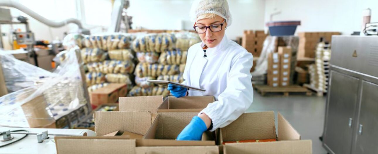 woman wearing protective gear while checking an order in a food processing warehouse