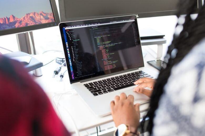 looking over the shoulder of a developer at the code on her laptop