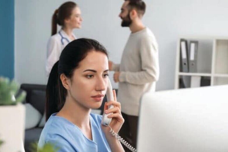 Female healthcare provider wearing scrubs talking on landline phone