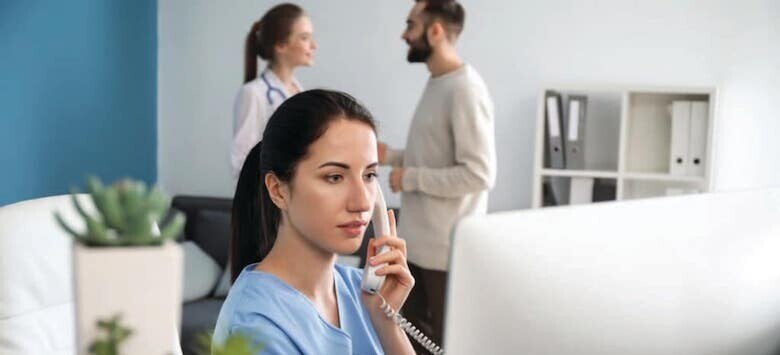 Female healthcare provider wearing scrubs talking on landline phone