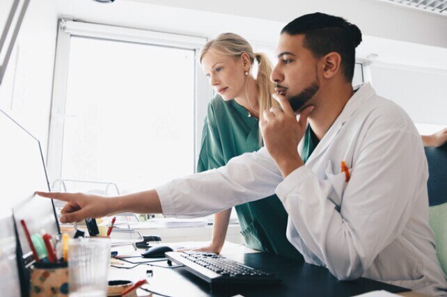 doctor pointing out something on a computer screen to a nurse