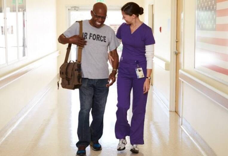 nurse assisting veteran walking down hallway