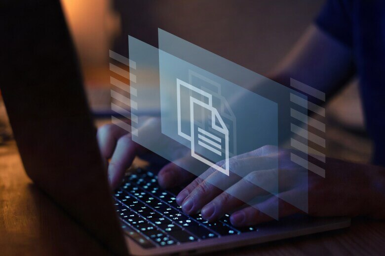 hands typing on the keyboard of an open laptop