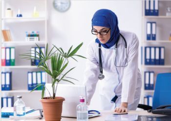 female doctor wearing blue hajib and looking at computer