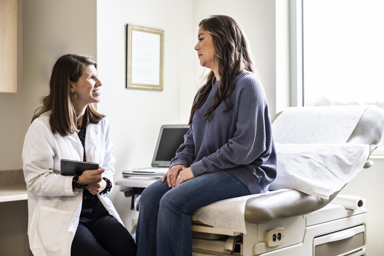 Female doctor sitting with female patient in exam room
