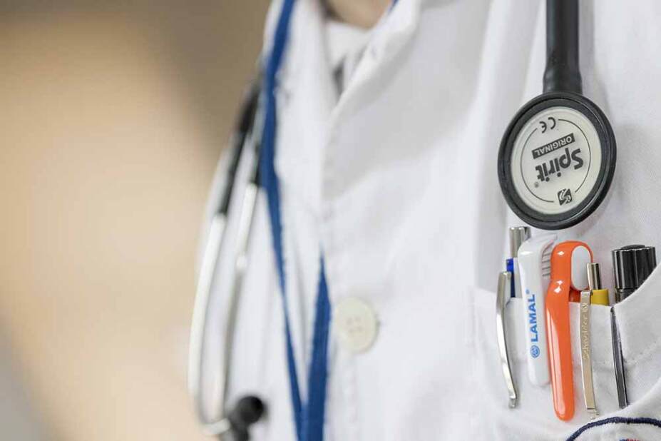medical doctor wearing a white coat and stethoscope, focus on the pens in their pocket