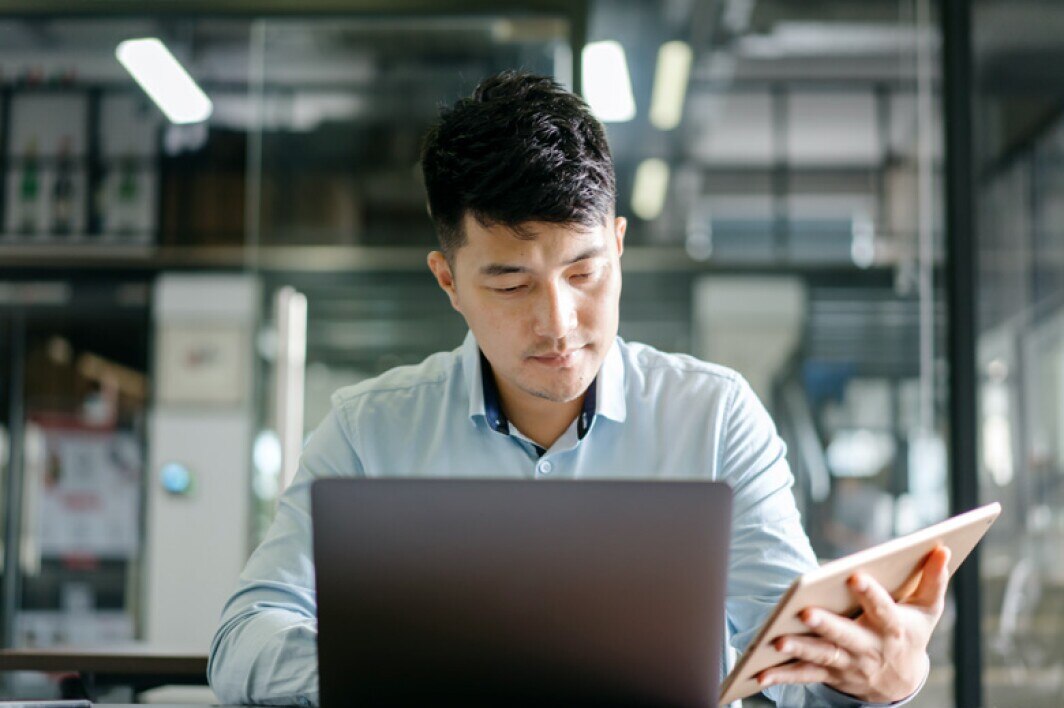 man sitting at desk looking at laptop