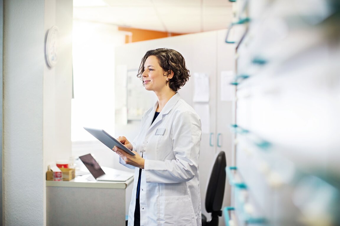 Female doctor holding a tablet in a hospital office and looking out in the distance