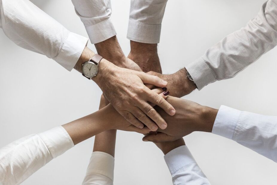 business colleagues stack their hands in the center to demonstrate teamwork