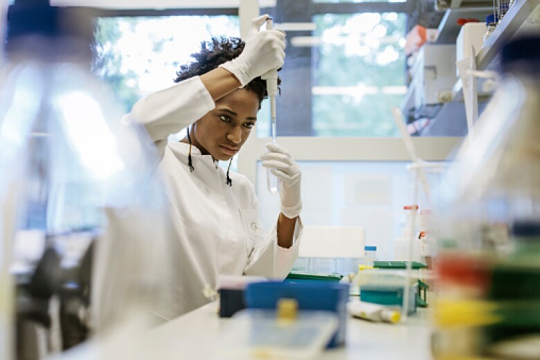 A black female scientist is pipetting in a laboratory.