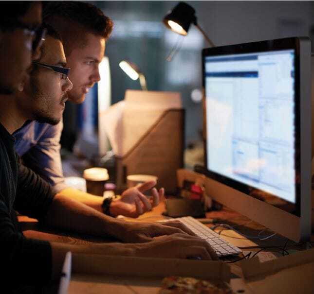 group of developers studying information on a computer screen