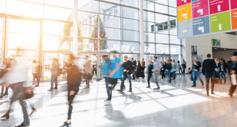 crowd of people moving fast through a modern lobby area