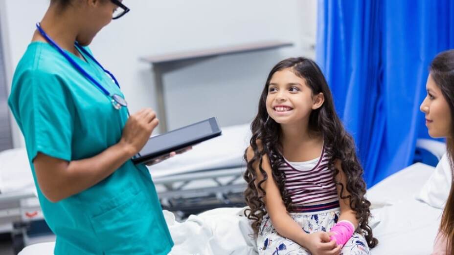 nurse speaking with young girl and her mother in exam room