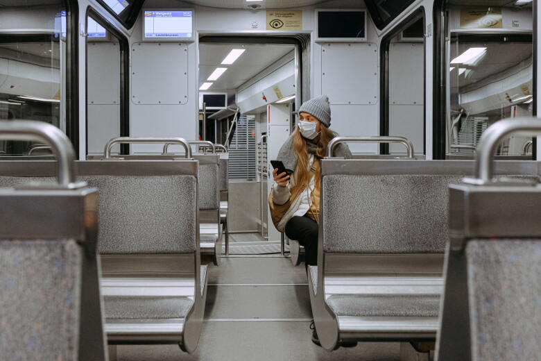 woman wearing protective face mask sits along on a subway