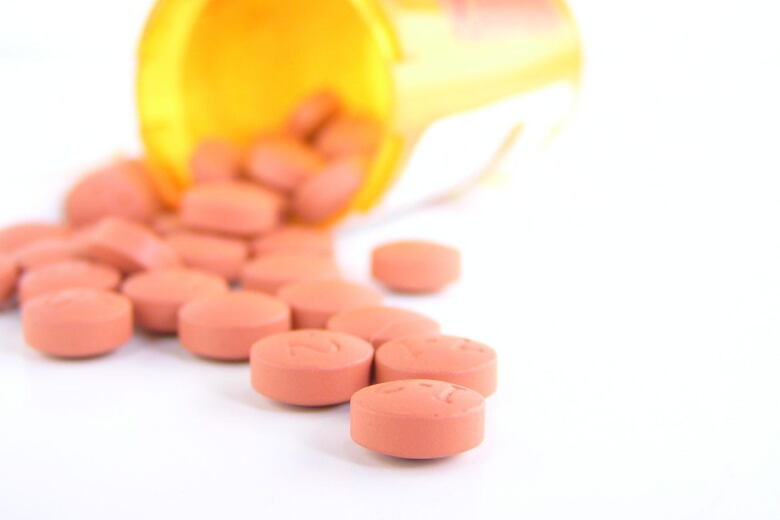 prescription bottle laying on its side with red tablets spilling out