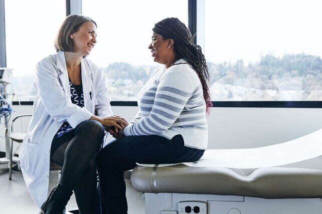 female doctor holding the hands of female patient in exam room