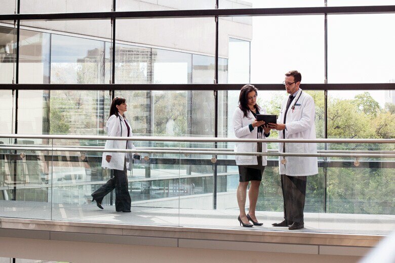 doctors reviewing information on a tablet in a hospital hallway