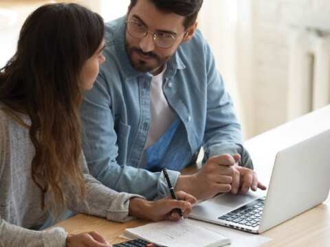 couple discussing their finances while working on a laptop