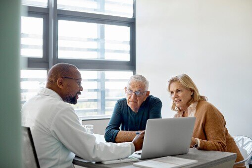Male doctor showing senior couple how to use online patient portal