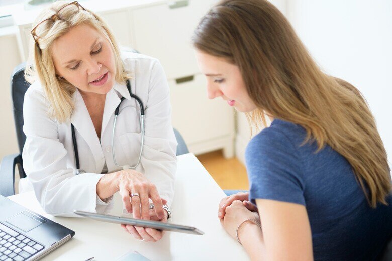 doctor looking at information on a tablet with young female patient