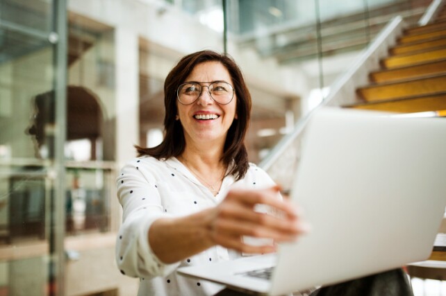 business woman smiling while finishing work on her laptop