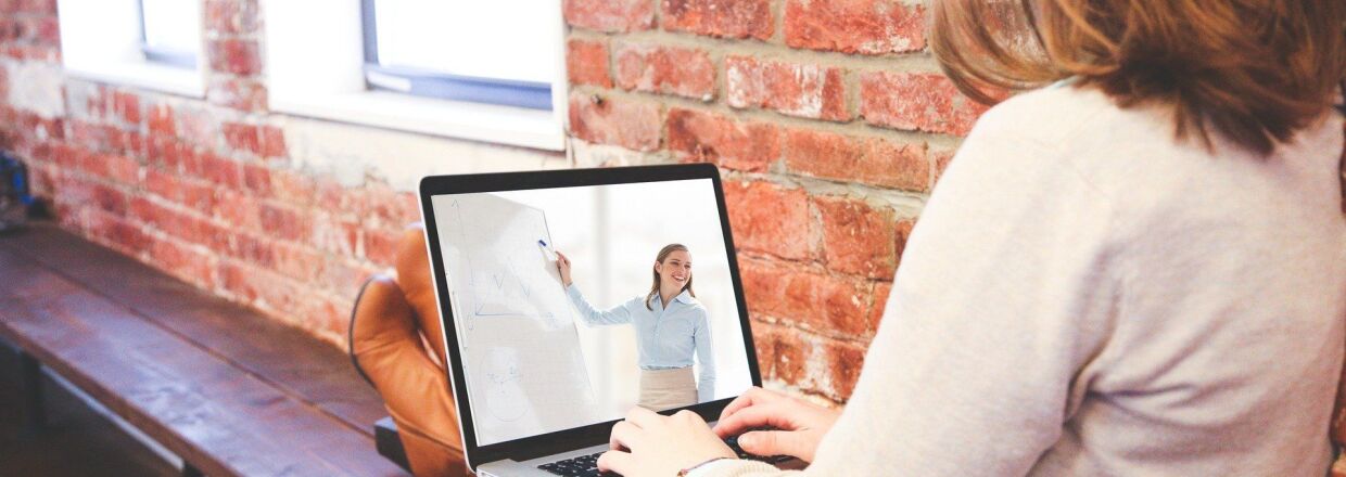 woman watching a presenter speak during a webinar on her laptop
