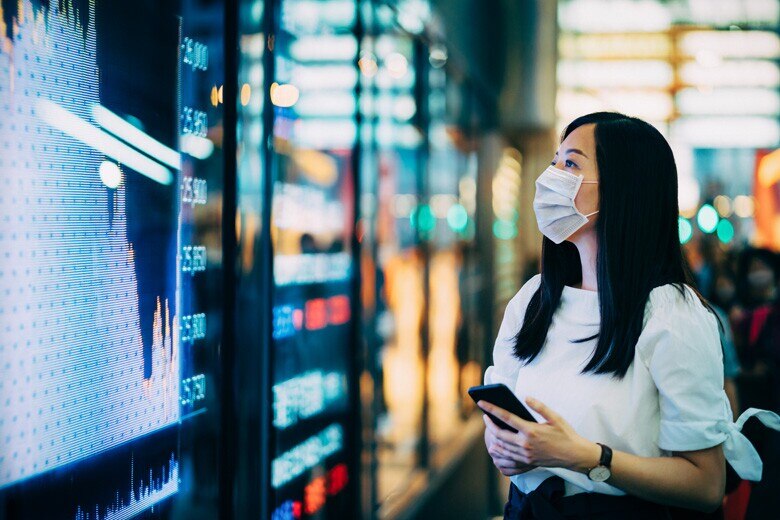 lady wearing a mask looking at financial data on a screen