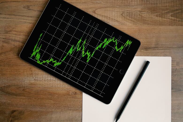 aerial view of a desk with blank paper, pen and tablet showing a line graph