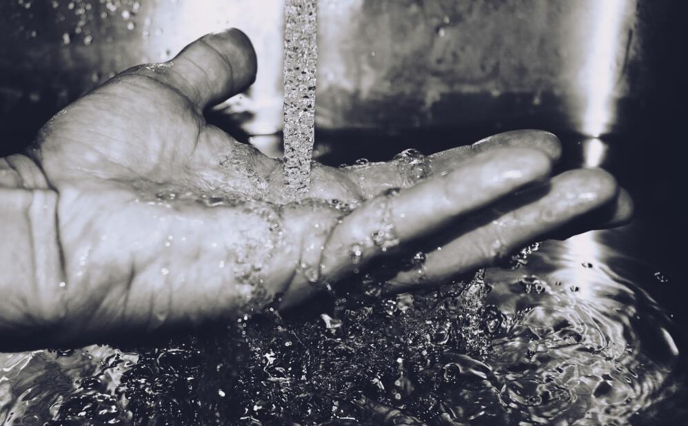 grayscale, close-up image of water running over a person's open palm