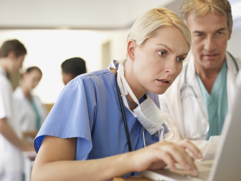 Nurse typing on computer with male doctor