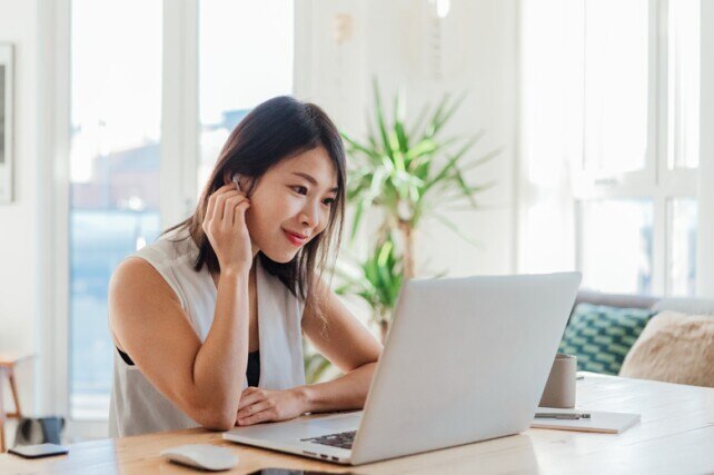 young woman taking a virtual class on her laptop at home