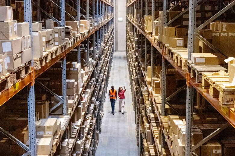 Two workers in a warehouse, illustrating the complex logistics MAO aims to streamline through AI-driven planning.