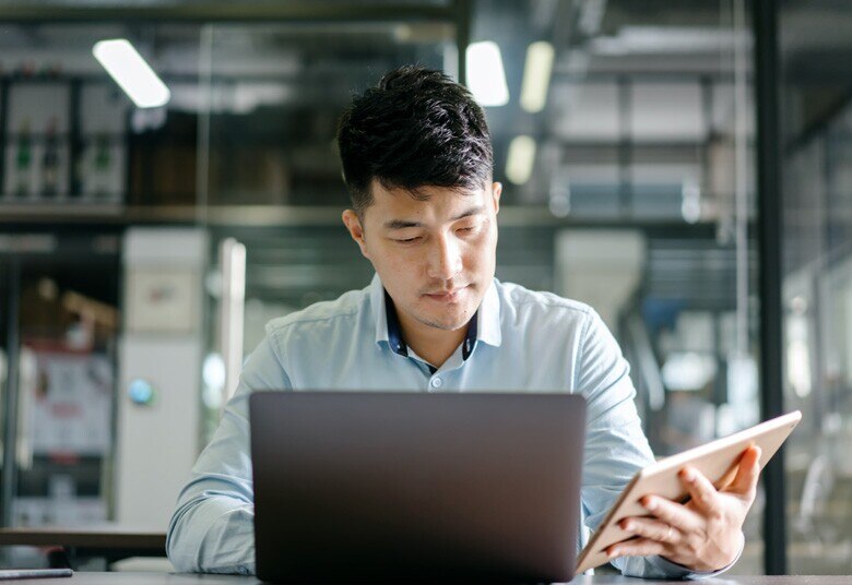 man sitting at desk looking at laptop