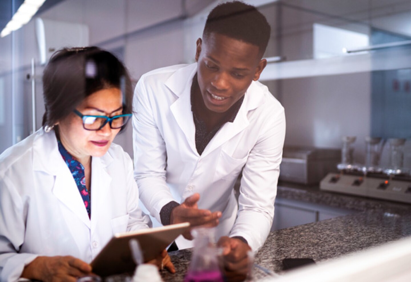 lab techs looking at health data on a tablet