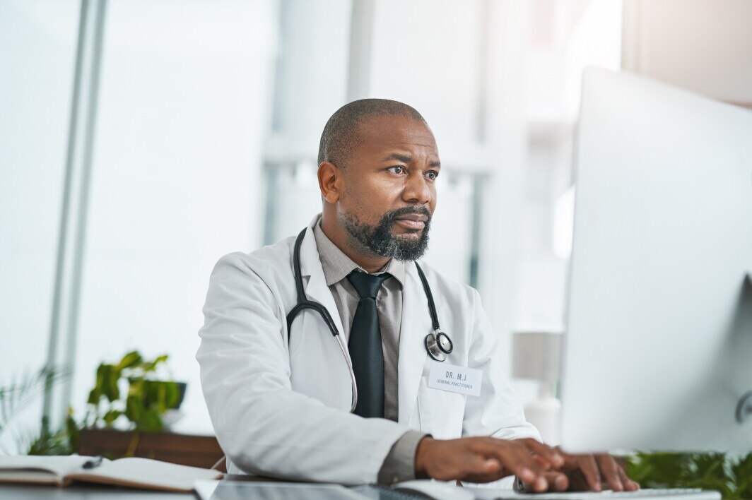 male doctor reviewing EHR at his computer