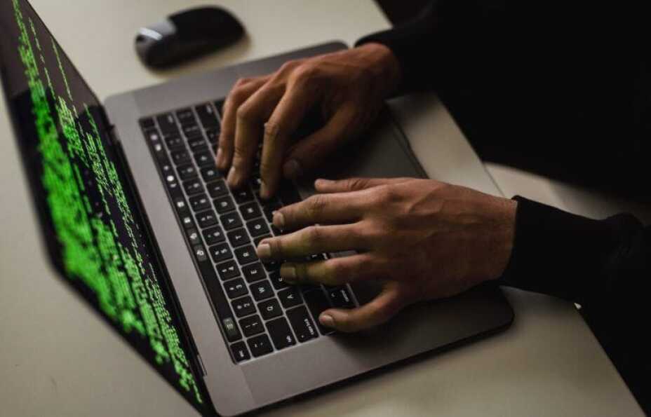 two hands of an IT developer typing on his laptop computer