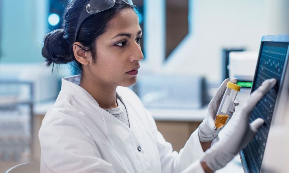 Woman lab tech at monitor with sample container