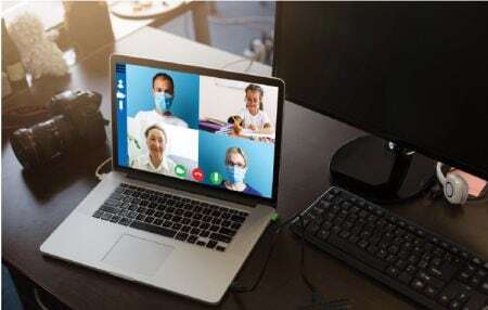 laptop on a desk showing a video call between three providers and a young patient