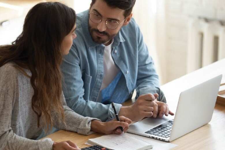 couple discussing their finances while working on a laptop