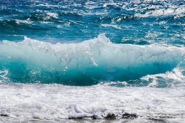 small waves in a turquoise ocean breaking on the shore