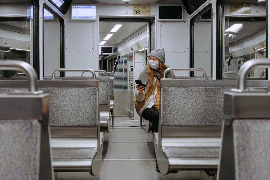 woman wearing a mask sits alone on a train during the pandemic
