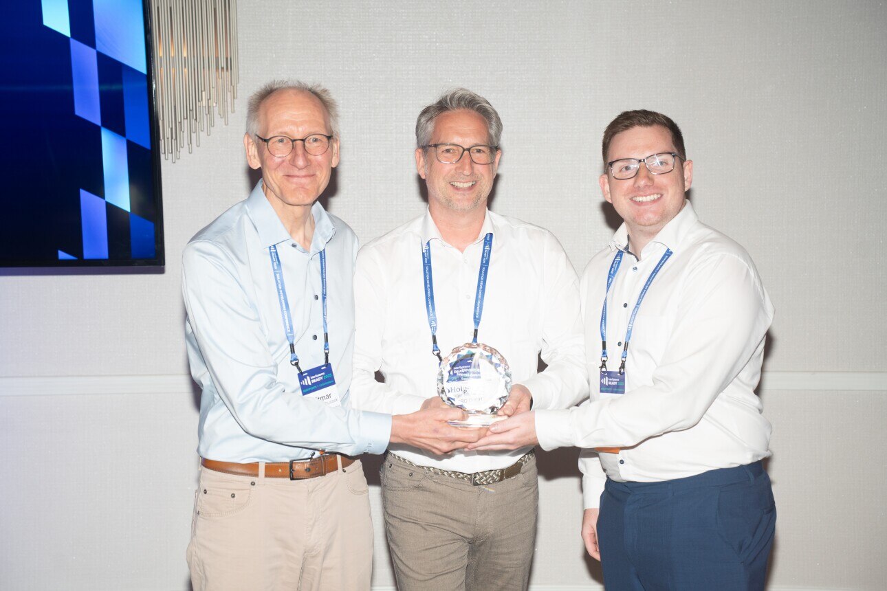 Three award winners from AGIMERO GmbH stand together holding their Impact Award