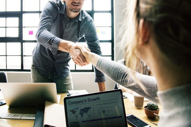 colleagues shaking hands across a desk